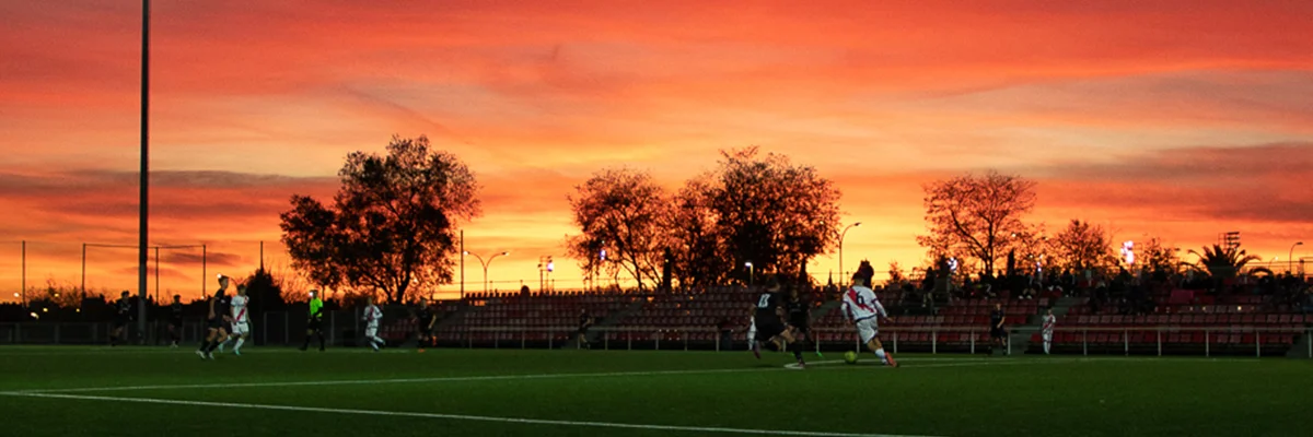 Soccer players running on field at sunset